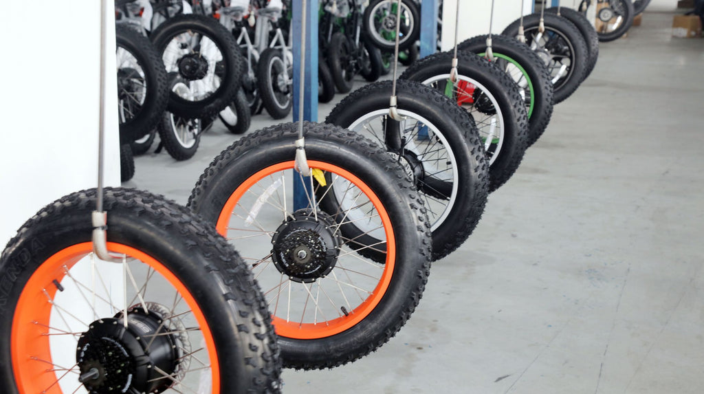 Display rack holds e-bike tires awaiting assembly in DAMAXED factory workroom.