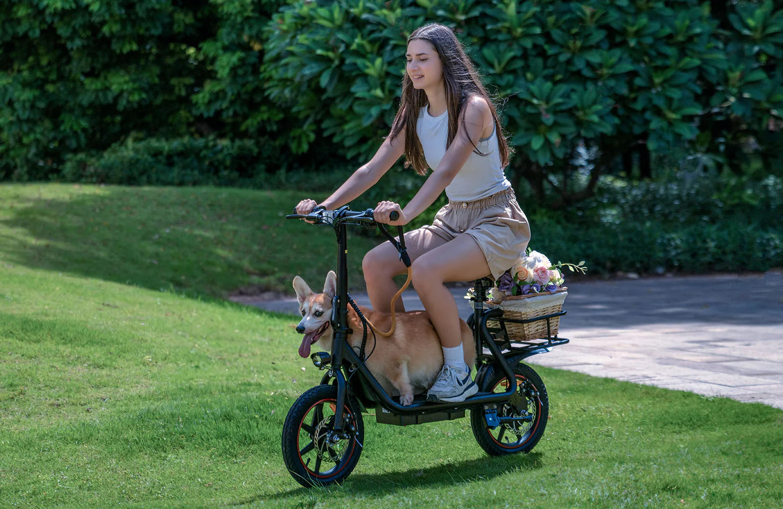 Woman riding a DYU C4 e-scooter with a dog in a pet seat on a grassy area