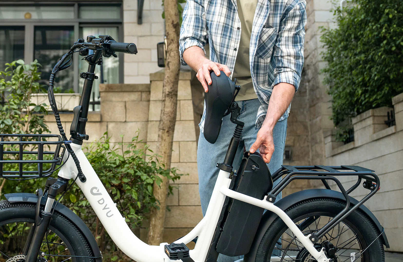 Person adjusting a white DYU C9 electric bike with a basket in an urban setting