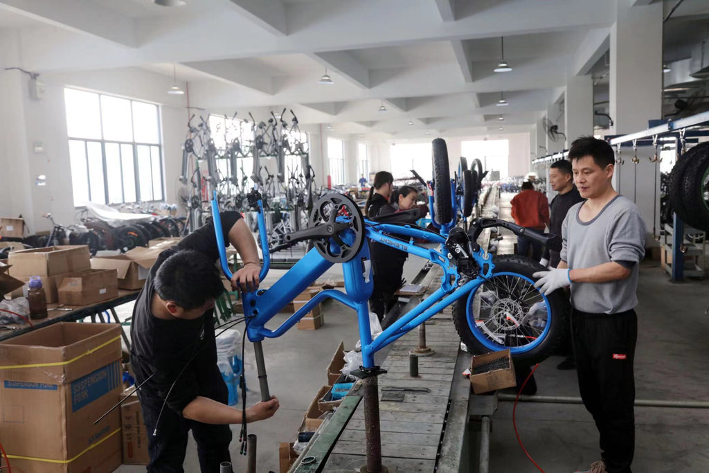 Six engineers orderly assemble blue e-bikes on production line with neatly arranged background.