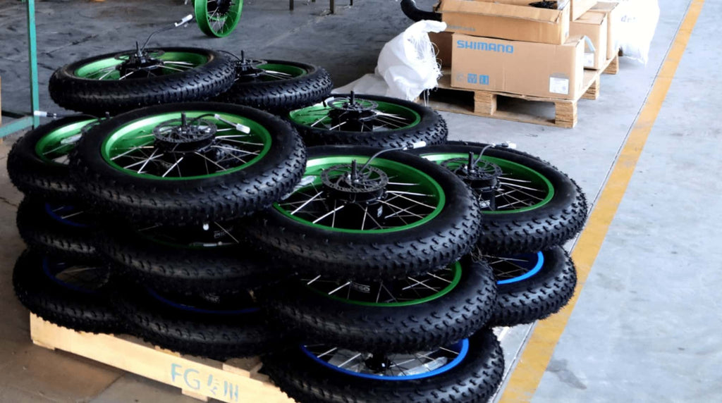 E-bike tires neatly stacked on the ground, paper boxes with Shimano parts placed behind them.