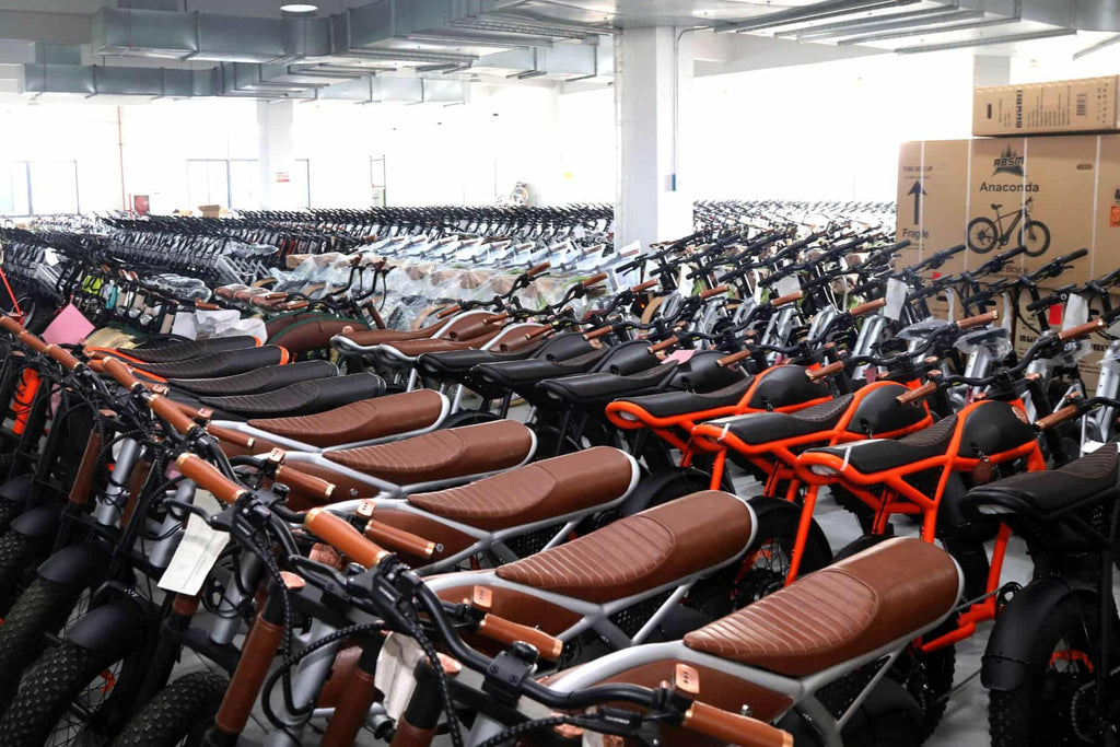 Rows of electric retro bikes with leather saddles, packed boxes for shipment, and assembled bikes awaiting inspection in Damaxed warehouse.