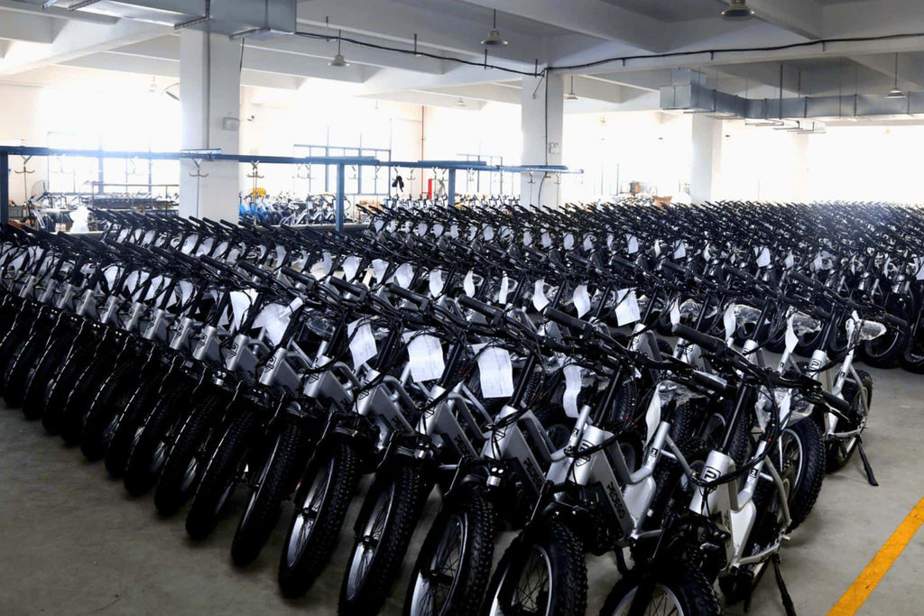 Damaxed warehouse: Rows of silver electric fat tire bikes waiting for quality inspection.