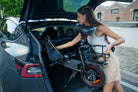 Woman loading a DYU C4  e-scooter into the trunk of a car