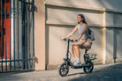 Woman riding a DYU C4  e-scooter on a city street with a building in the background