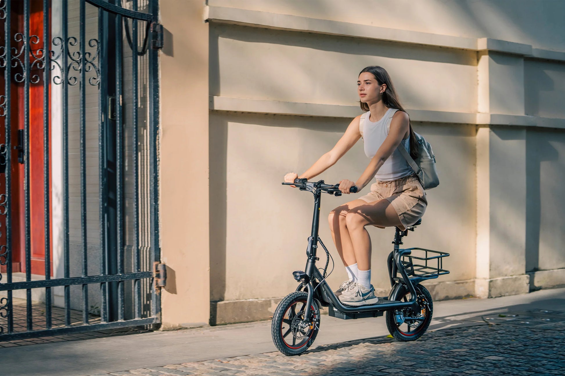 Woman riding a DYU C4  e-scooter on a city street with a building in the background