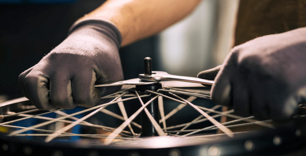 DAMAXED electric bike assembly worker carefully inspecting tire quality and safety with gloves.